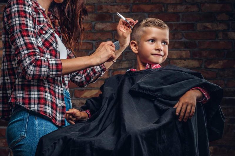 smiling-preschooler-boy-getting-haircut-children-hairdresser-with-scissors-and-comb-is-cutting-little-boy-in-the-room-with-loft-interior